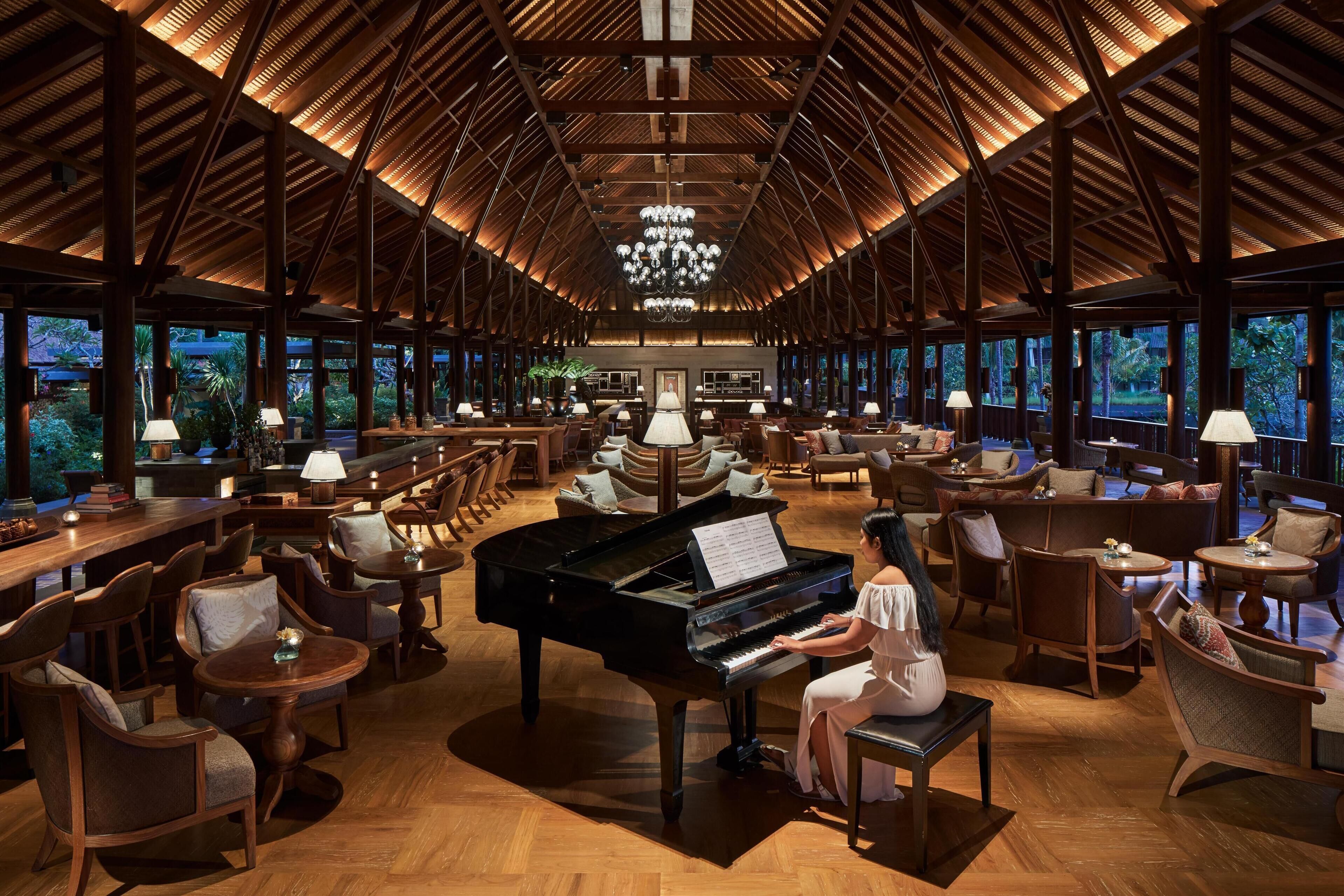 A spacious lobby with a grand piano, comfortable seating, and large windows offering views of the outdoors.