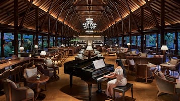 A spacious lobby with a grand piano, comfortable seating, and large windows offering views of the outdoors.