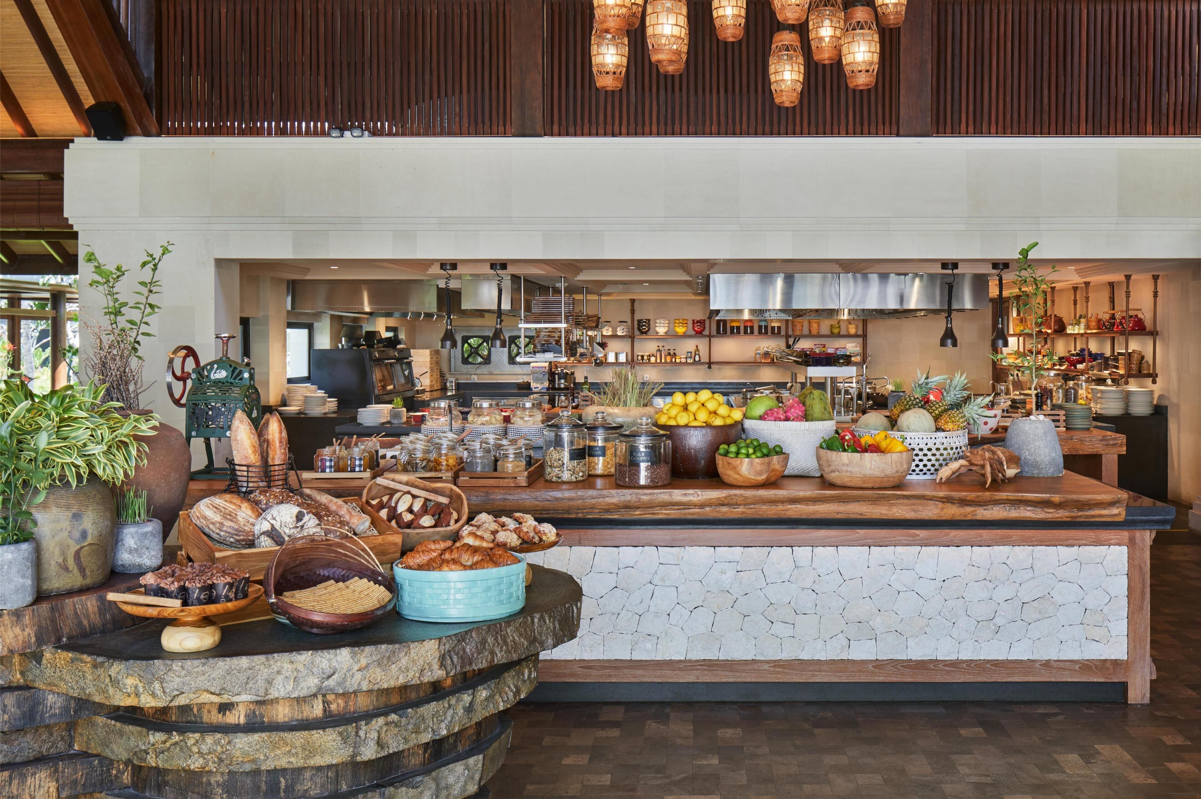 Uma área de buffet com diversos tipos de comida e uma cozinha ao fundo.