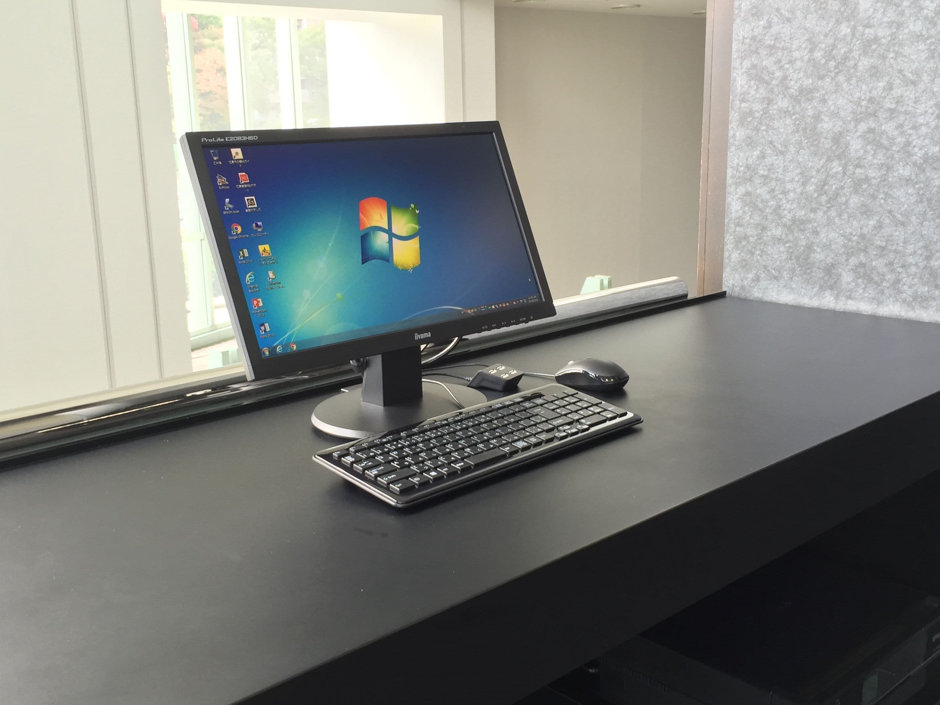 A ProLite C203HSD monitor on a black desk with a keyboard and mouse.