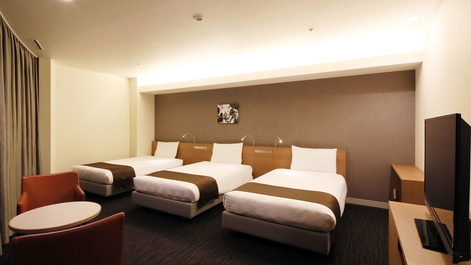 Una habitación de hotel con dos camas, un escritorio, una silla y un televisor.