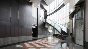 A modern hotel lobby with a checkered floor, a staircase, and a large windowed wall. - Hiroshima Tokyu REI Hotel (Hiroshima)