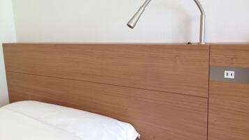 Una cama con ropa de cama blanca, cabecera de madera y un grifo moderno encima.