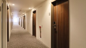 A hotel hallway with carpeted floors, wooden doors, and recessed lighting. - Hiroshima Tokyu REI Hotel (Hiroshima)