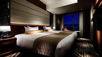 A hotel room with a large bed, two bedside tables, a nightstand, a lamp, and a view of the city at night.