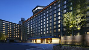Un hotel moderno con gran número de habitaciones, una entrada destacada y una fachada bien iluminada.