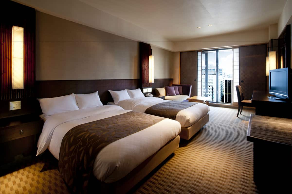 Une chambre d’hôtel avec deux lits, un bureau et une télévision.