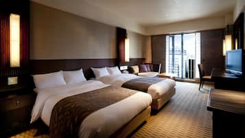 A hotel room with two beds, a desk, and a TV.