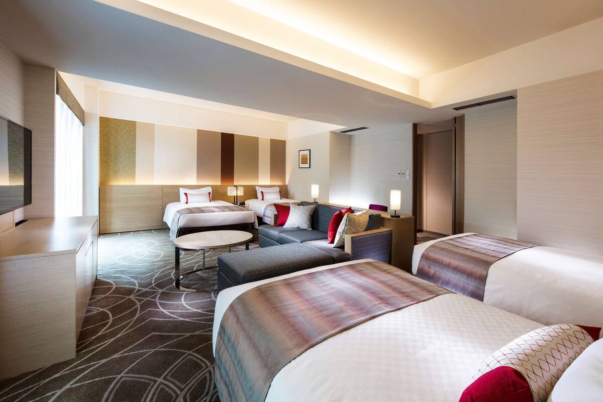 Une chambre d’hôtel avec deux lits, un canapé, un bureau et une télévision.
