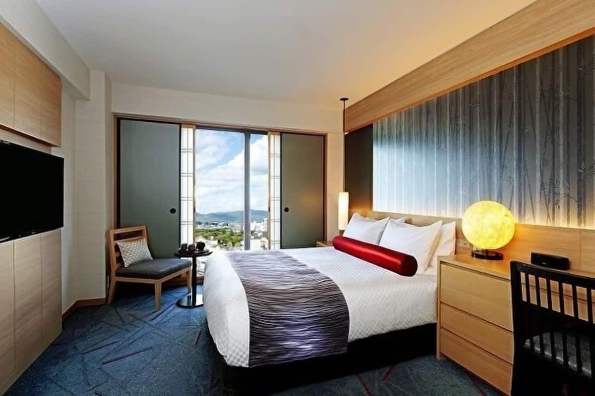 Une chambre d’hôtel moderne dotée d’un grand lit, d’un bureau, d’une chaise, d’une télévision et offrant une vue sur la ville.