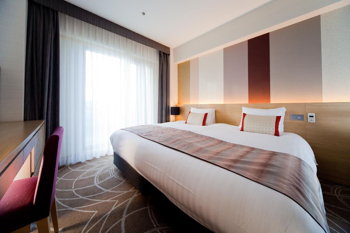 Une chambre d’hôtel avec un grand lit, un bureau et une chaise.