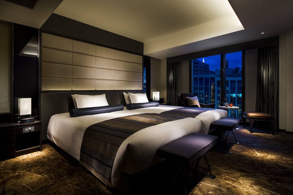 Une chambre d’hôtel moderne dotée d’un grand lit, d’un coin salon et offrant une vue sur le paysage urbain.
