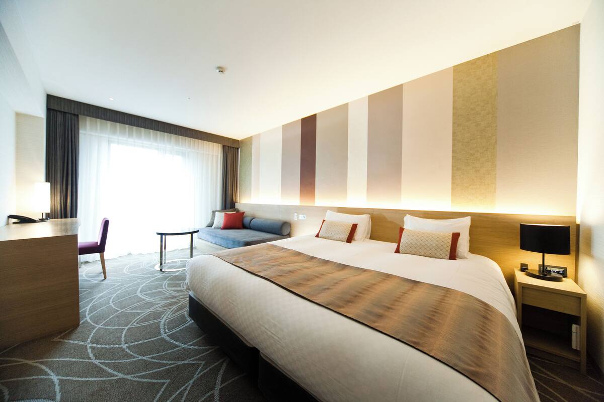 Une chambre d’hôtel avec un grand lit, un bureau, une chaise et un canapé.