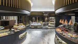 Un área de buffet moderna con múltiples estaciones de comida, un expositor central y una encimera curva de mármol.