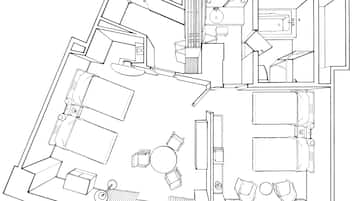 A detailed floor plan of a hotel room with a bed, a desk, a chair, a small table, and a bathroom with a sink and toilet.