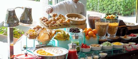 A buffet with various food items and a chef preparing food.