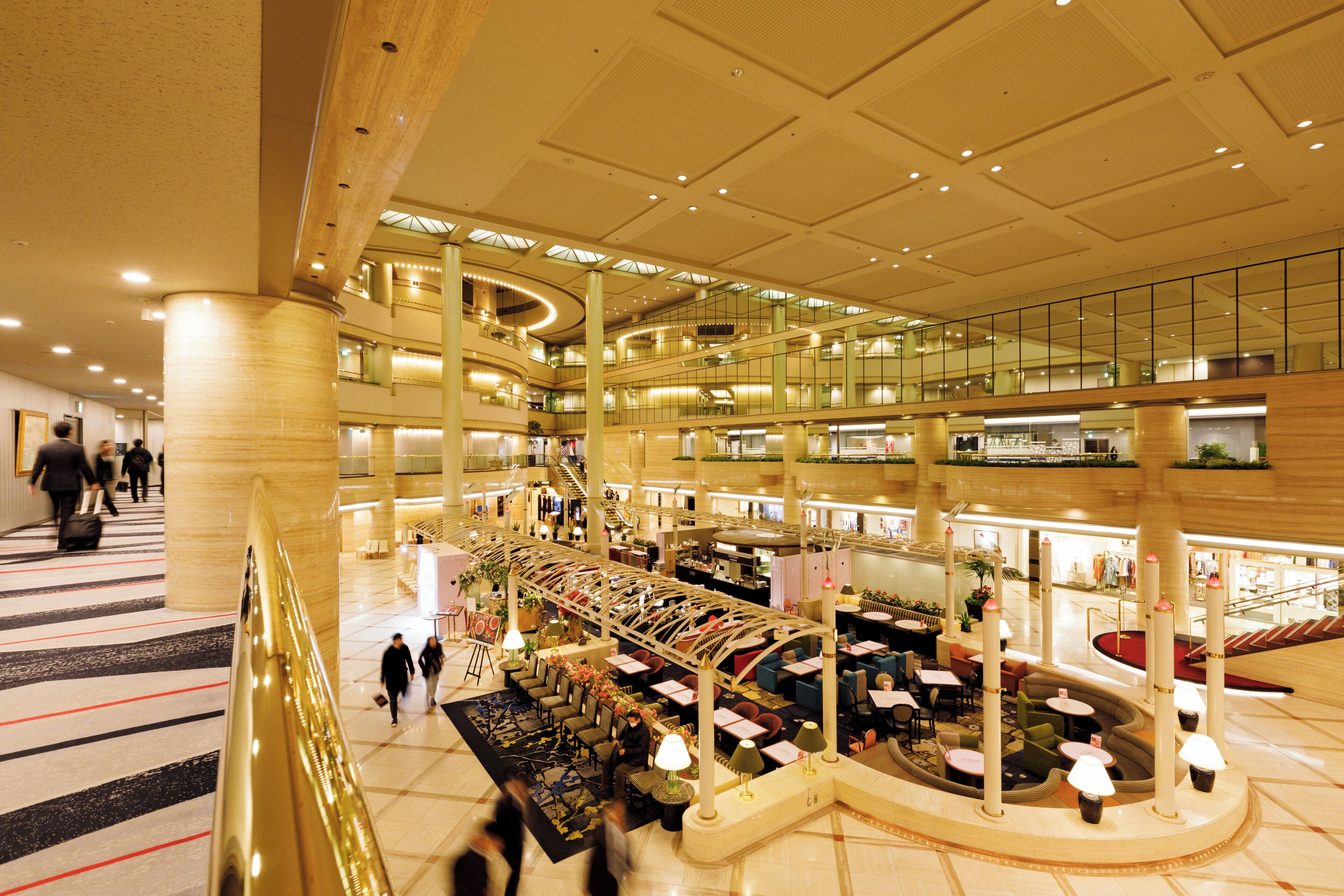 Rebost d'hotel de diverses plantes amb un atrium central, zones d'estar i una escala.