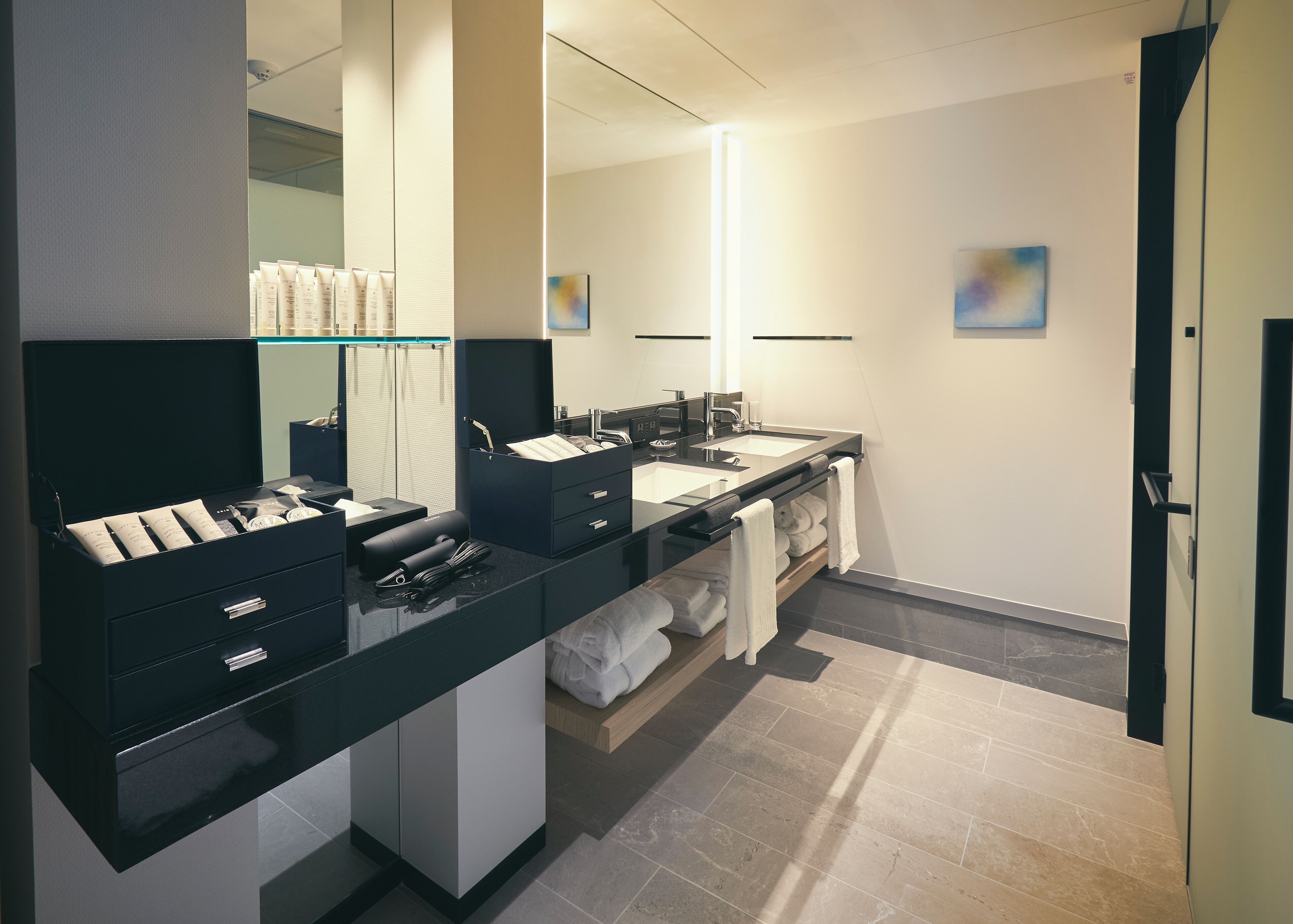 A modern bathroom with a black vanity, a large mirror, and a double sink.