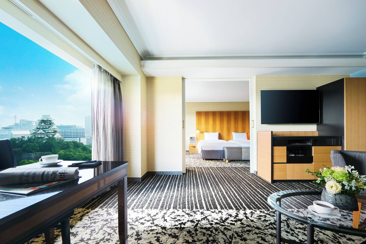 Una camera d'albergo con un letto, una televisione, una scrivania e vista sulla città.