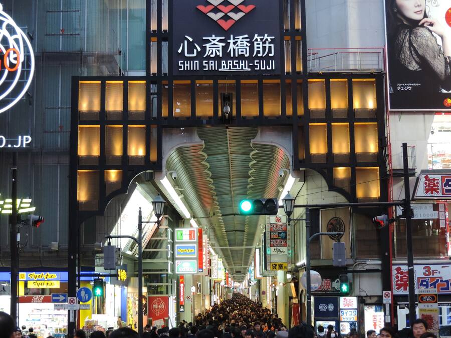 A busy urban street with a prominent building featuring a large, illuminated sign.