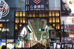 A busy urban street with a prominent building featuring a large, illuminated sign.