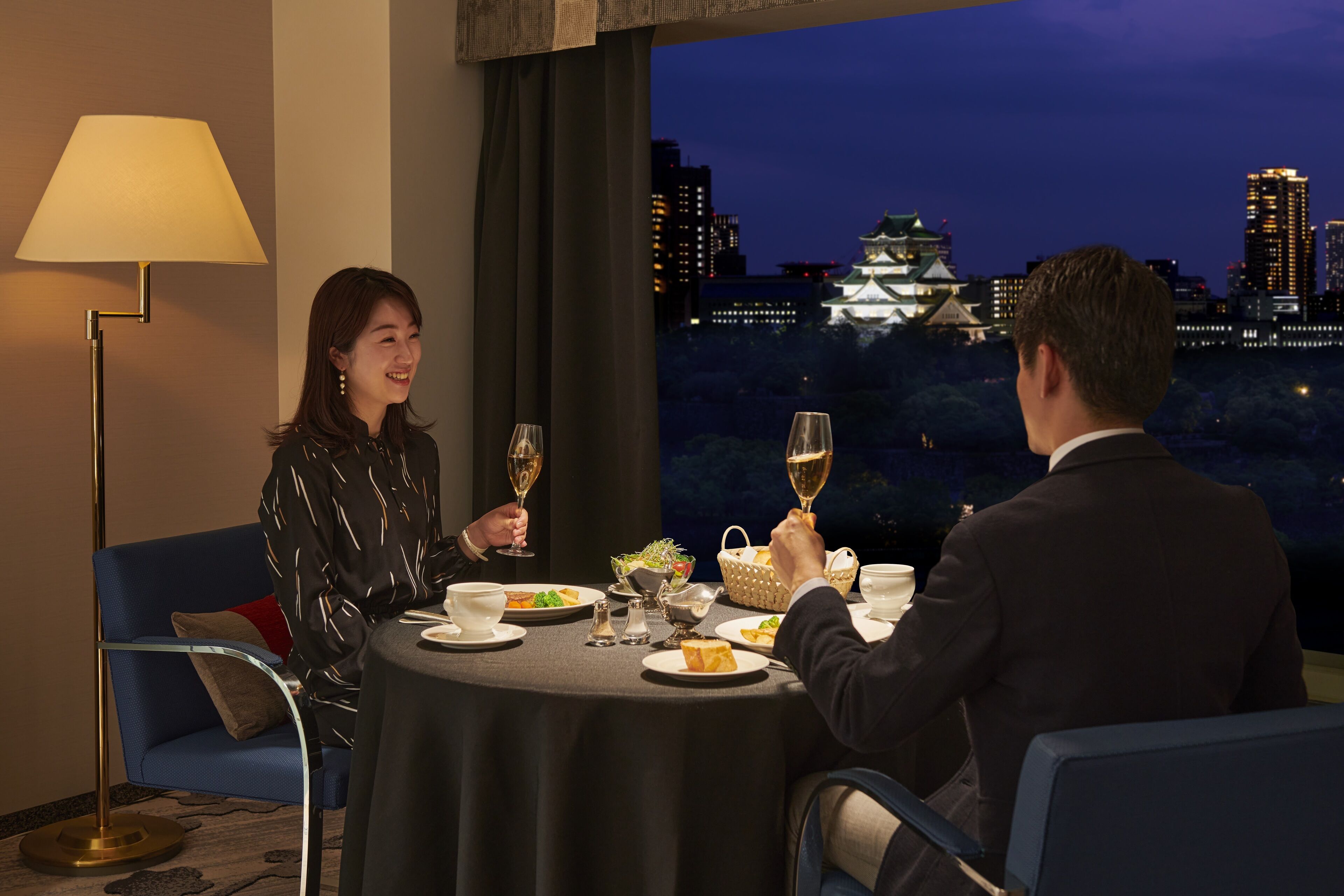 A dining table with a view of a cityscape at night.