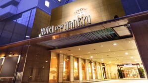 A hotel entrance with a modern design, featuring a prominent sign and a glass facade. - Hotel New Hankyu Osaka (Osaka)
