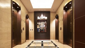A modern elevator lobby with a checkered floor, marble walls, and a skylight. - Hotel New Hankyu Osaka (Osaka)