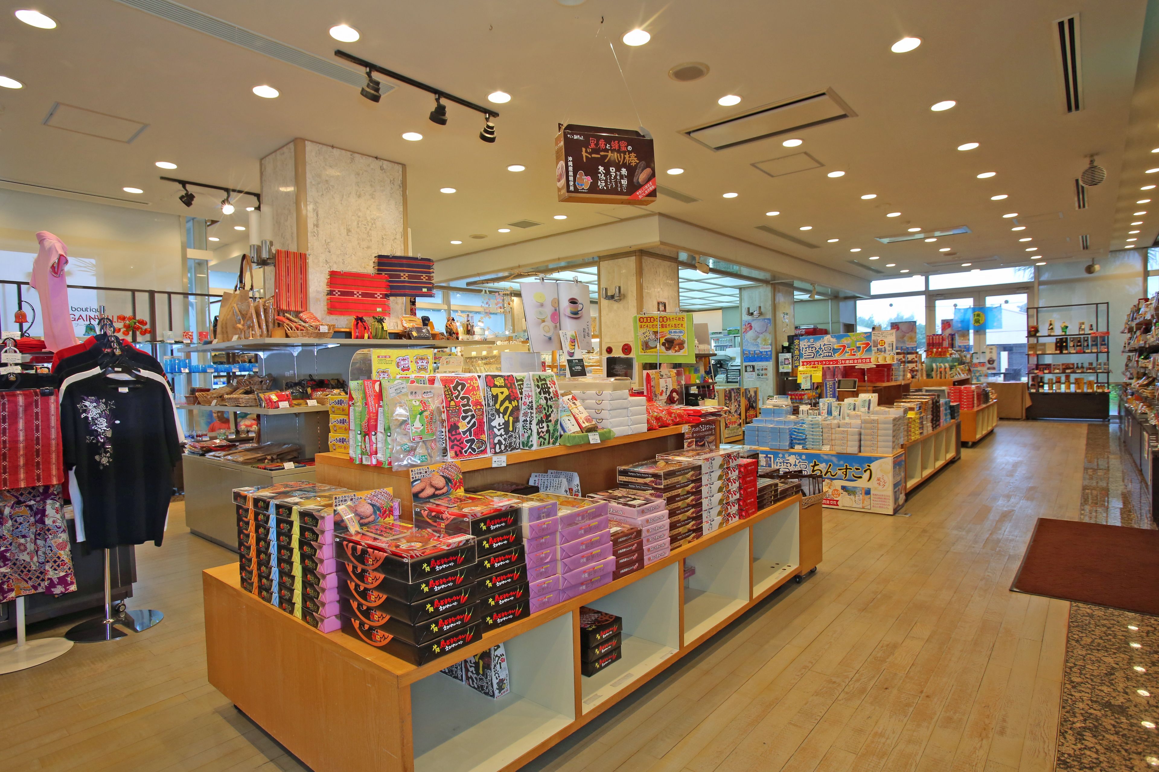 A retail store with various products on shelves and displays, including boxes and clothing items.