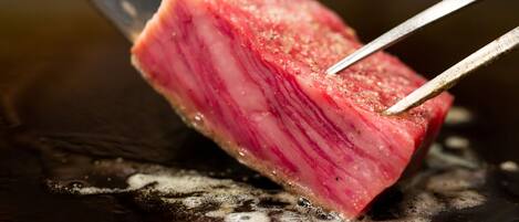 Primer plano de un trozo de carne asándose con pinzas.