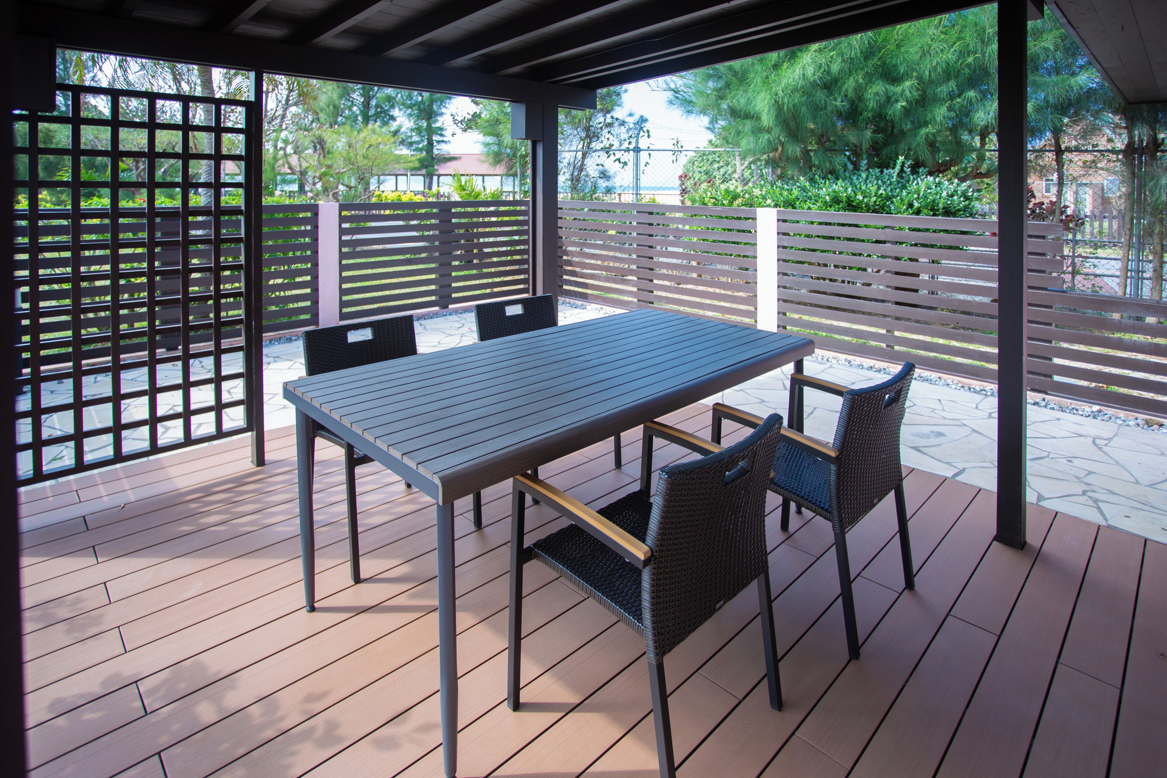 An outdoor patio with a table and chairs, surrounded by wooden fences and greenery.