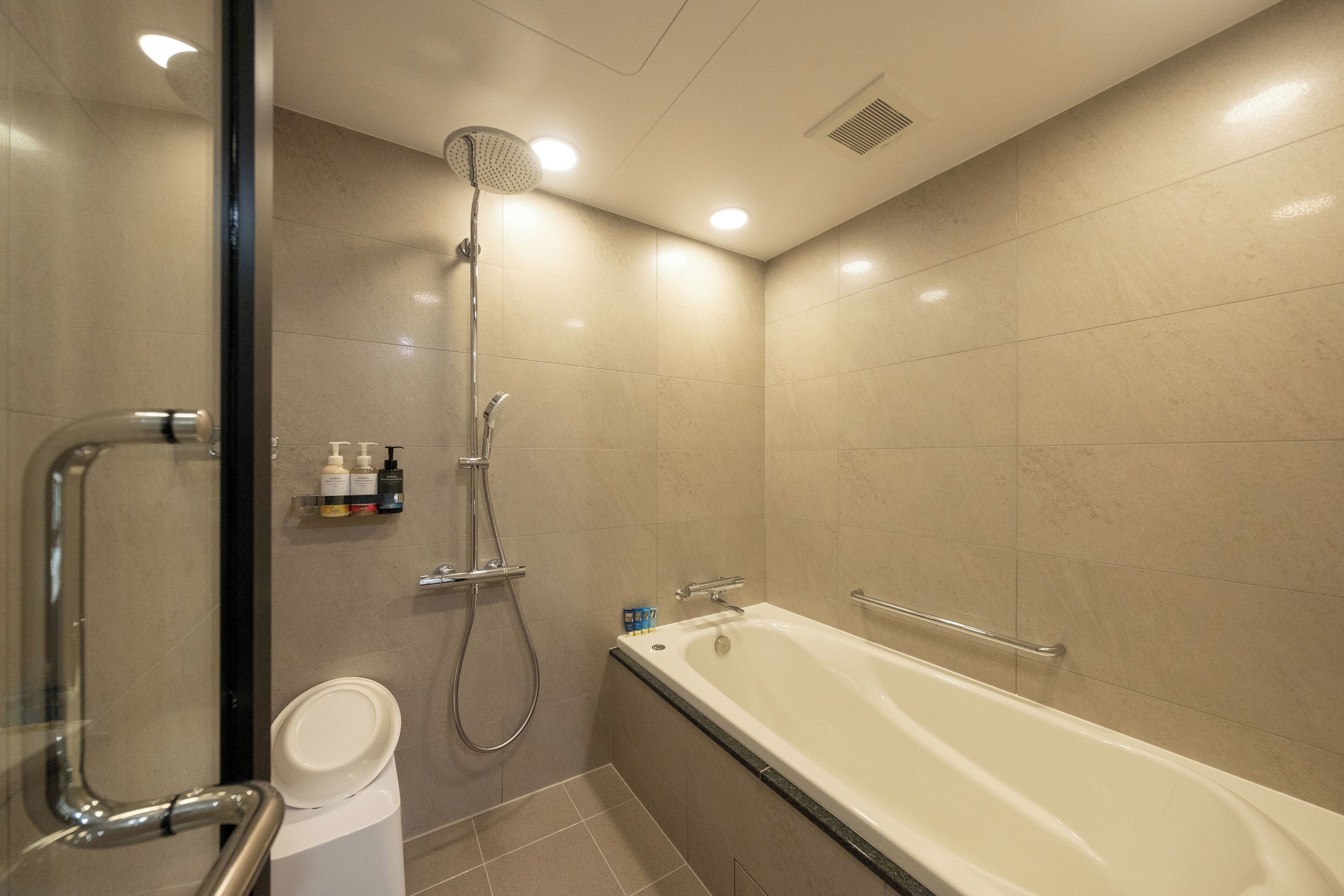 A modern bathroom with a bathtub, shower, and toilet.