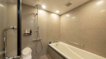 A modern bathroom with a bathtub, shower, and toilet.