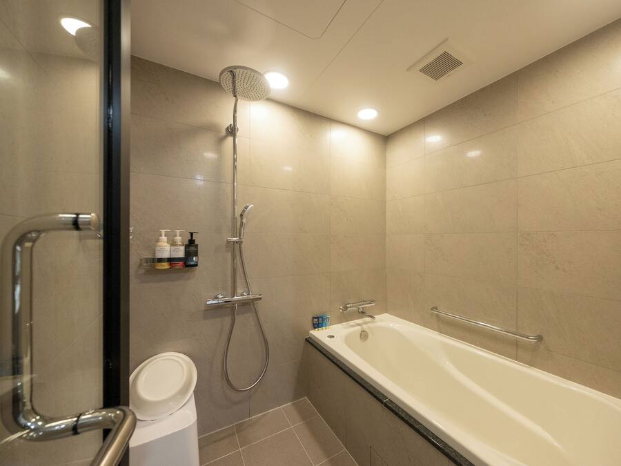 A modern bathroom with a bathtub, shower, and toilet.