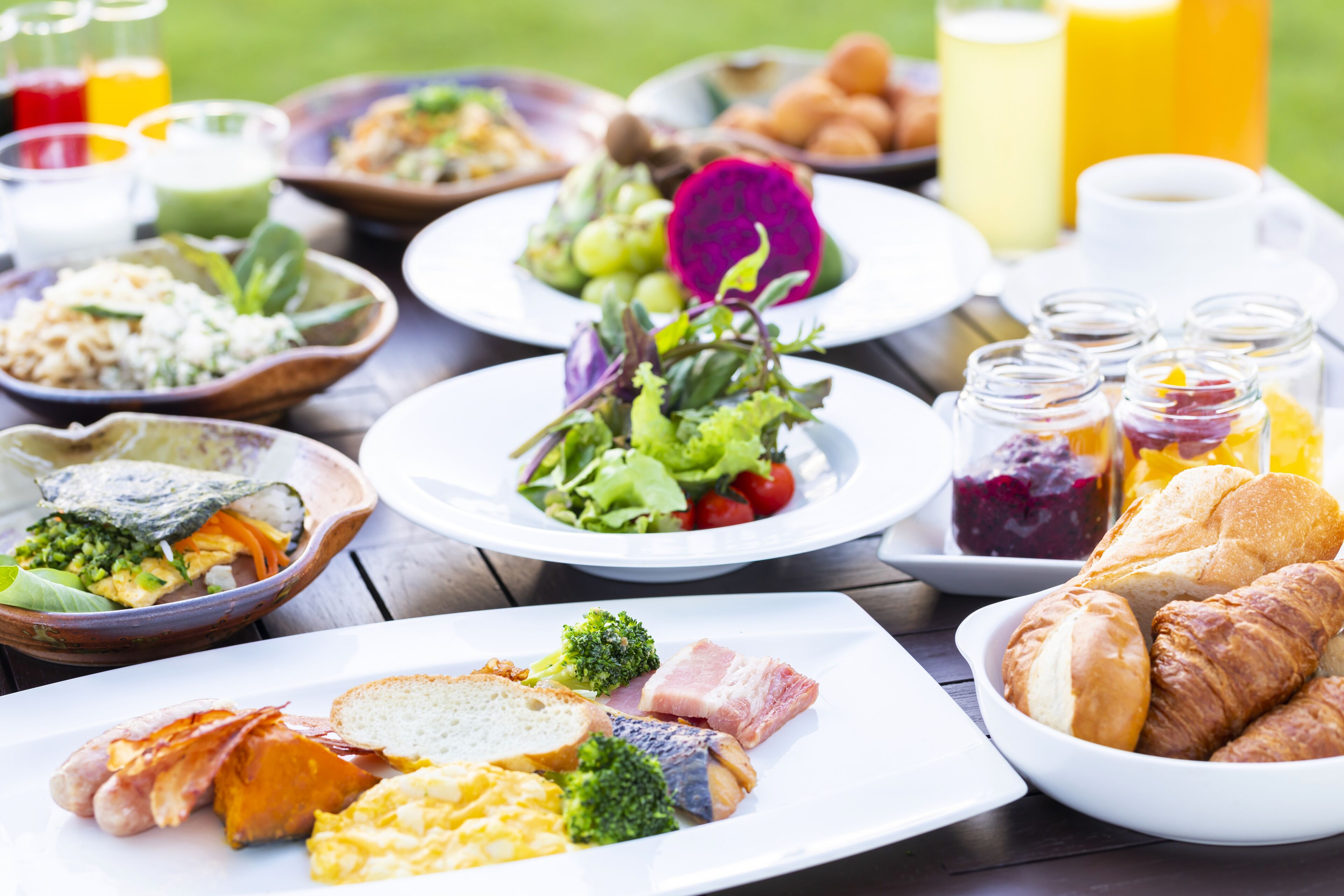 Variedad de platos para el desayuno, incluyendo huevos, tocino y verduras, sobre una mesa de madera.