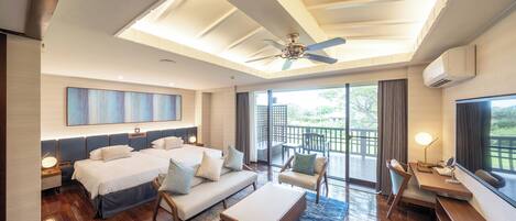 A modern hotel room with a large bed, a sofa, a desk, and a balcony with a view.