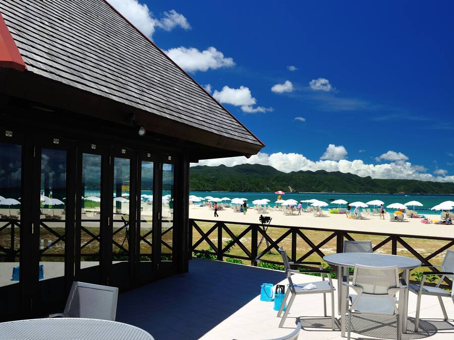 A beachside patio with outdoor seating and a view of the beach and mountains.