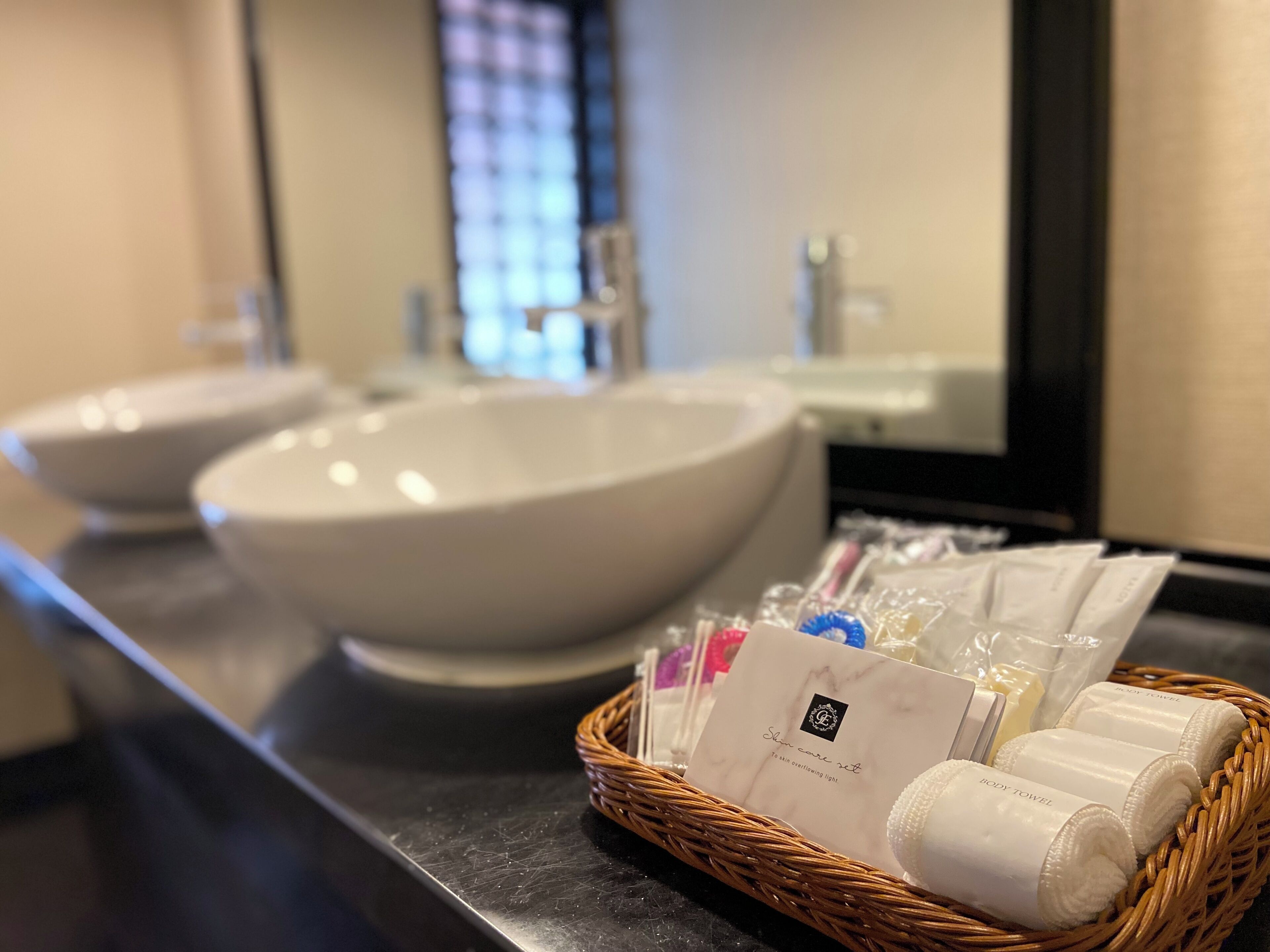 A bathroom with two sinks and a wicker basket containing toiletries.