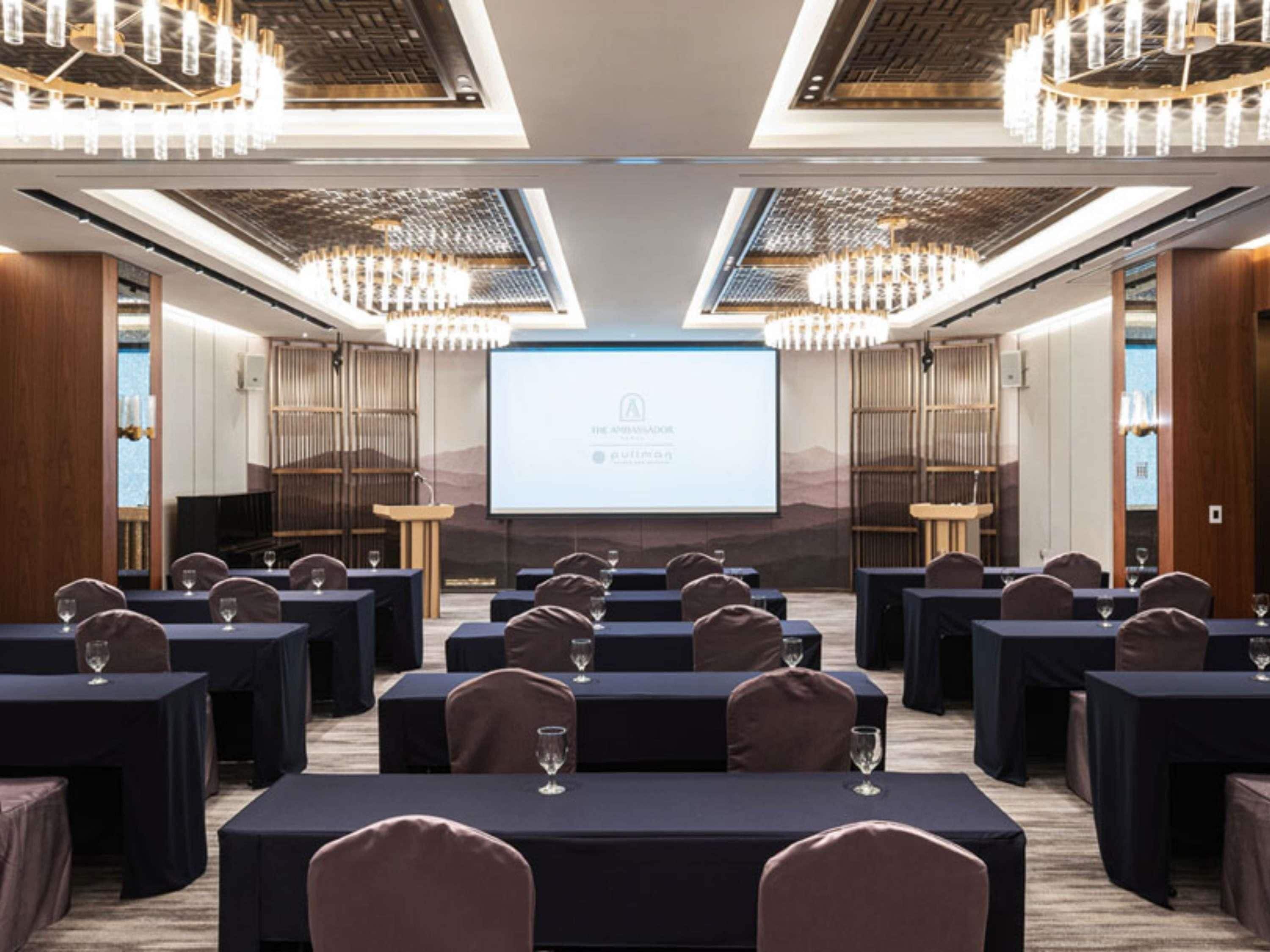 A conference room with tables, chairs, and a presentation screen.