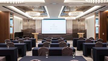 A conference room with tables, chairs, and a presentation screen.
