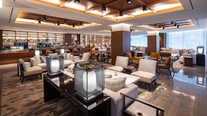 A modern lobby with a bar area, seating arrangements, and a large glass table with a decorative centerpiece. - The Ambassador Seoul - A Pullman Hotel (Seoul)