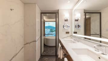 A modern bathroom with a large mirror, two sinks, and a view of a cityscape through an open door.