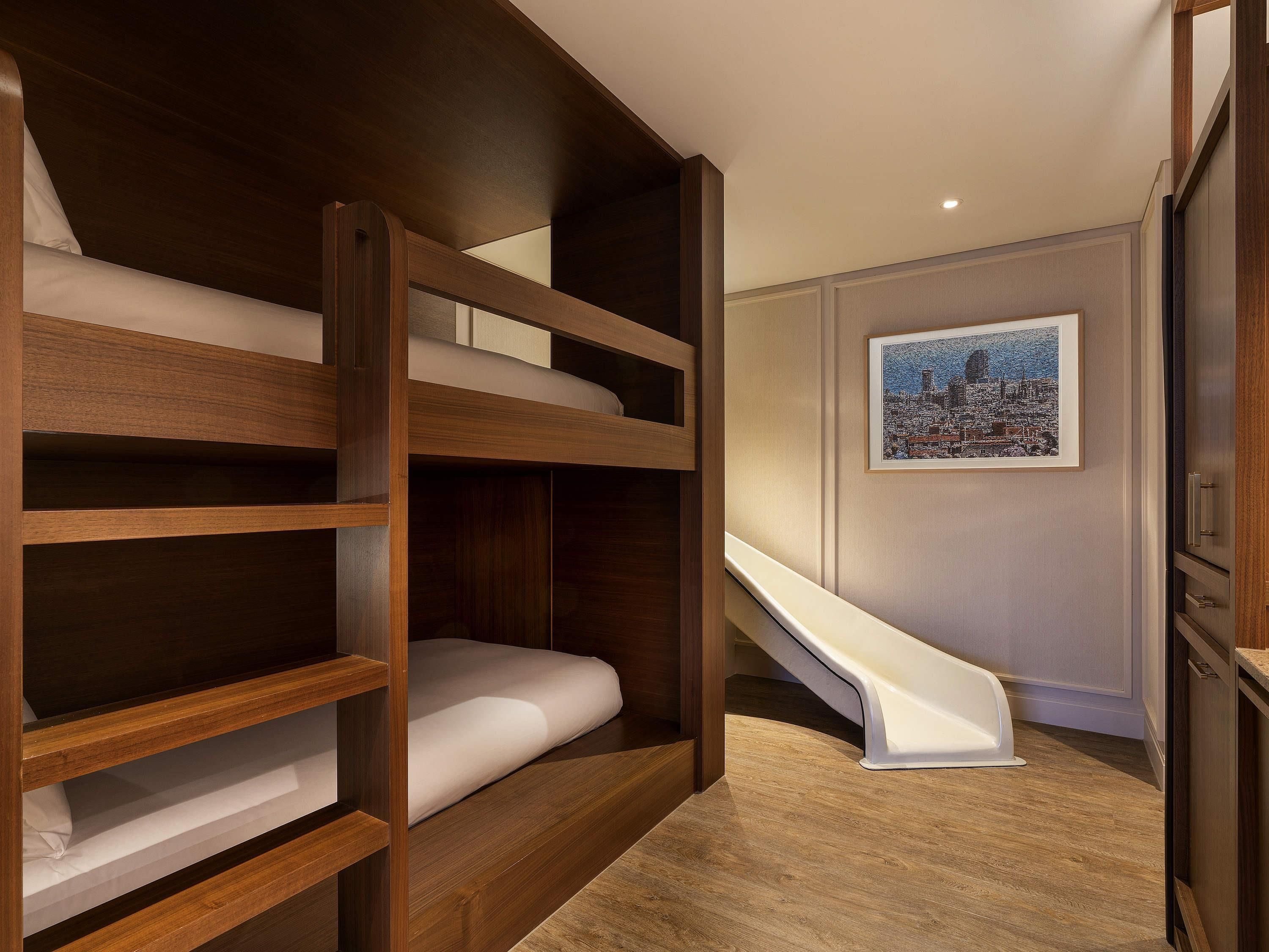 A bunk bed with a white mattress, a wooden ladder, and a white slide.
