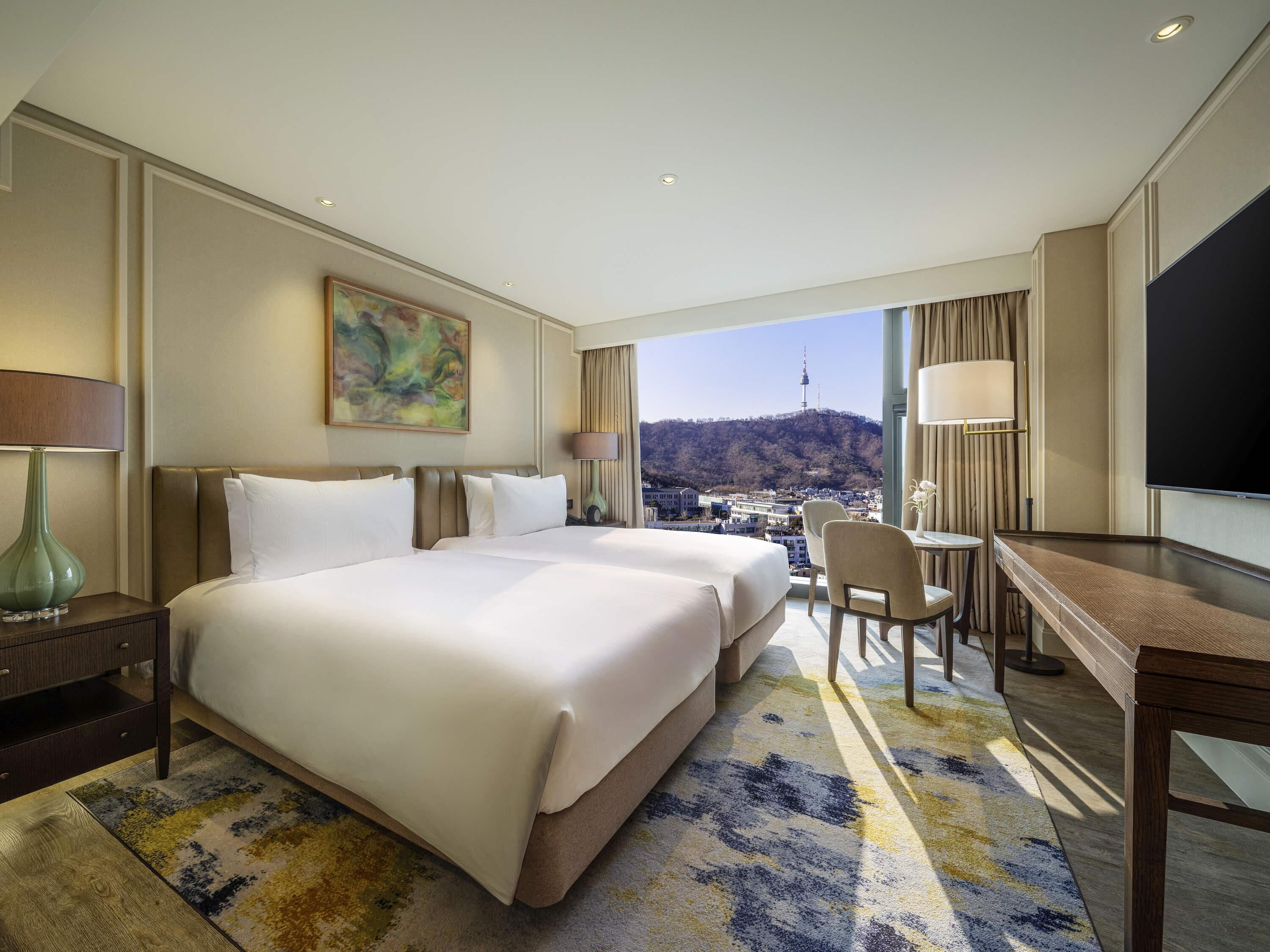 A hotel room with a large bed, a desk, a chair, and a TV.