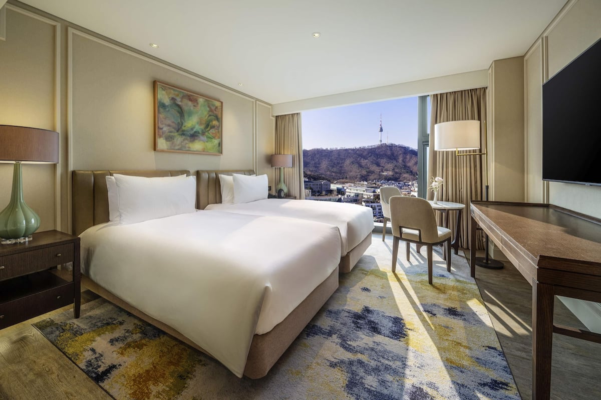 A hotel room with a large bed, a desk, a chair, and a TV.