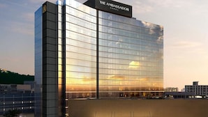 A modern hotel with a reflective glass facade, a prominent sign at the top, and a spacious entrance area with a covered walkway. - The Ambassador Seoul - A Pullman Hotel (Seoul)