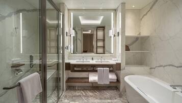 A modern bathroom with a glass-enclosed shower, a double sink vanity, a large mirror, and a freestanding bathtub.