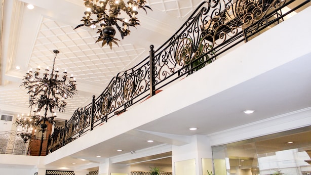Un atrium à plusieurs niveaux, agrémenté de balustrades en fer forgé noir ouvragé, de grands lustres et de murs en verre.