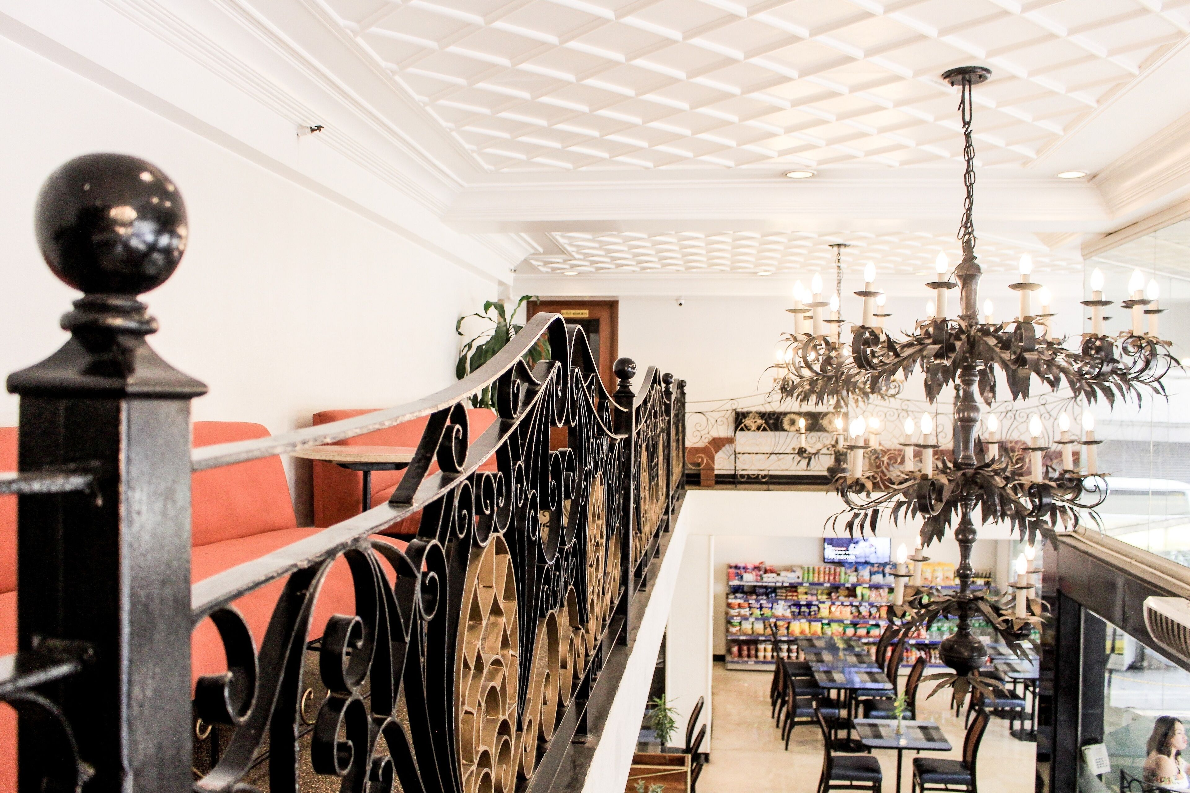 A restaurant with a high ceiling, ornate chandelier, and red seating.