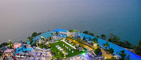 An aerial view of a resort with a pool, outdoor dining area, and a stage for events.